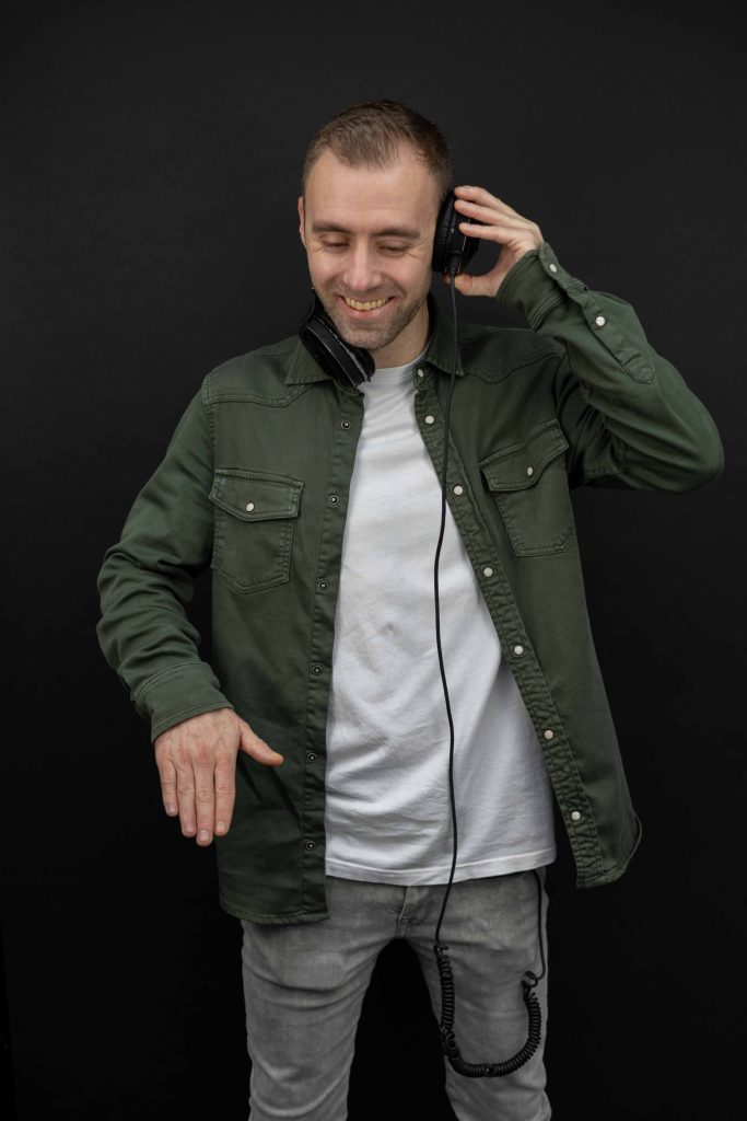 Dennis in een groen jasje met koptelefoon steekt beide duimen op.