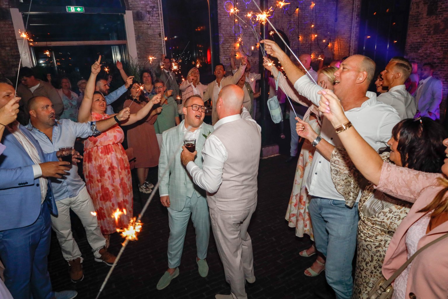 Bruiloftsgasten vieren feest met sterretjes op een volle dansvloer.
