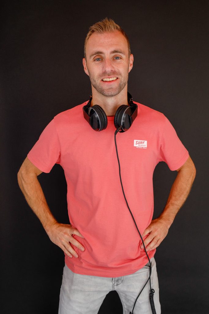 Dennis in een rood poloshirt met een koptelefoon rond zijn nek.