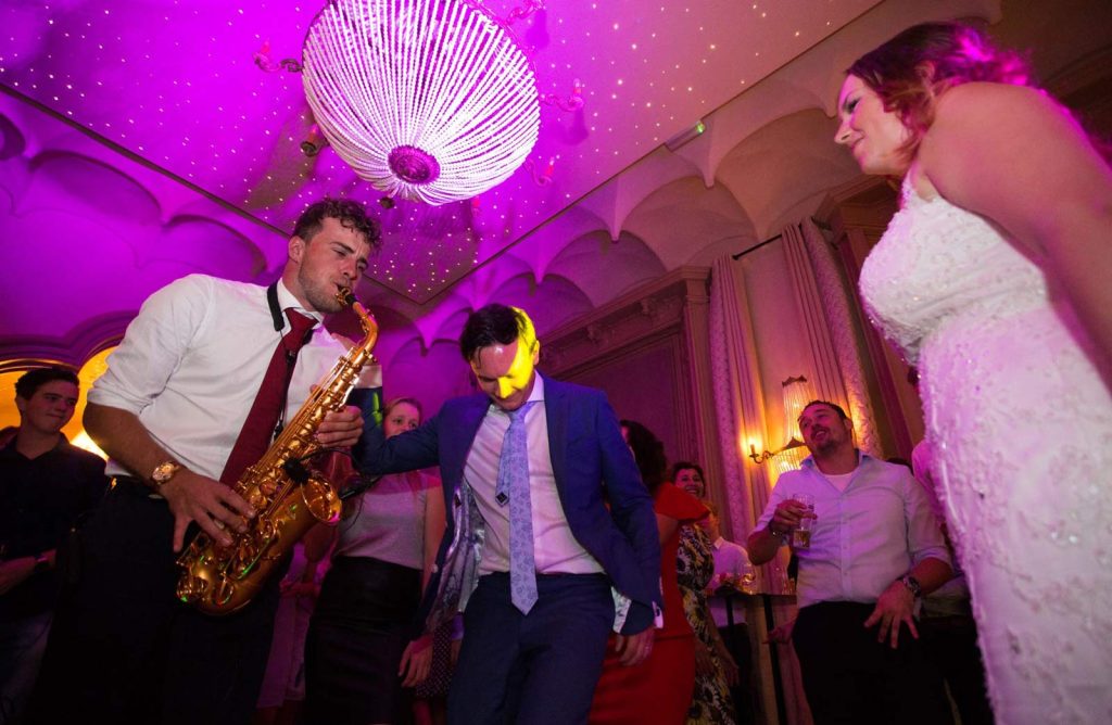Saxofonist Ivar speelt live tijdens een feest met roze sfeerverlichting.