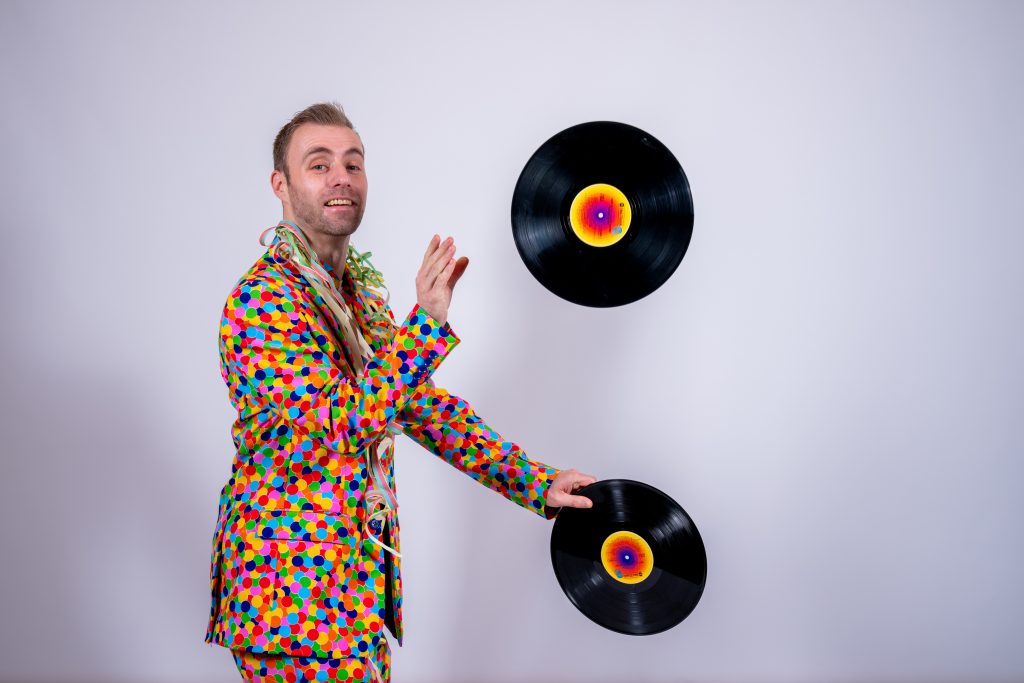 Dennis in een kleurrijk overhemd met vinylplaten tijdens een portretshoot.